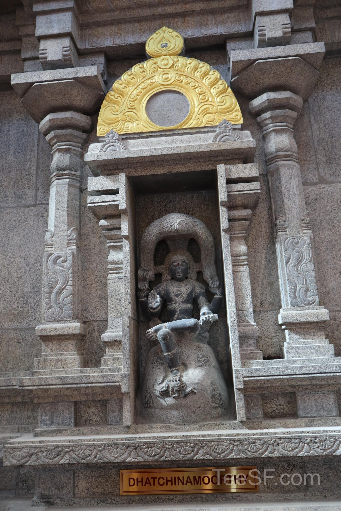 A dark stone shrine detail set into a gray carved wall.